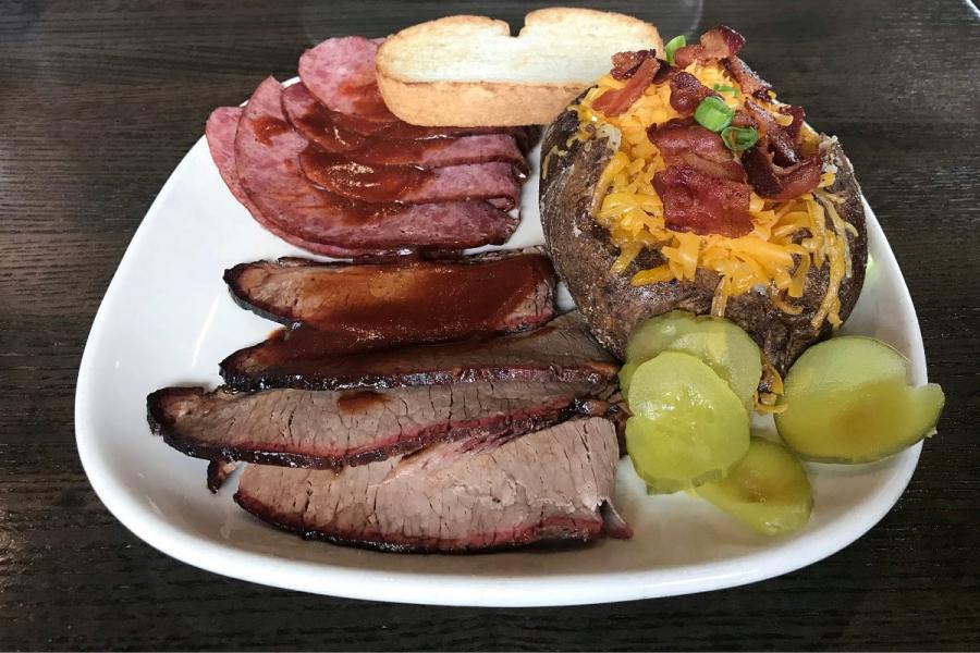 A plate filled with Kansas city barbecue meats and side dishes.